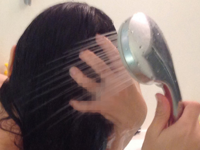 お湯で髪を洗っている女性